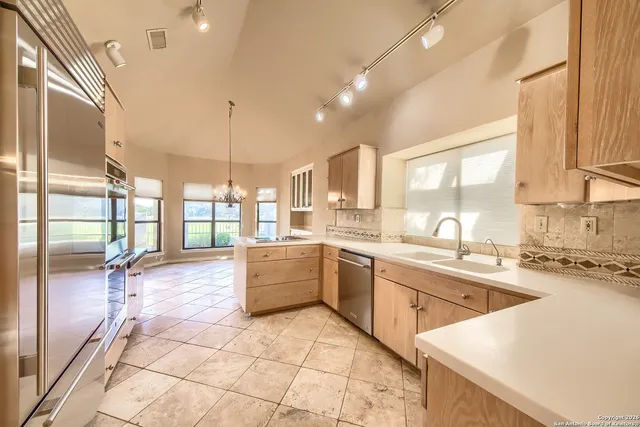 a large white kitchen with a large window and stainless steel appliances