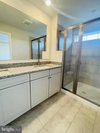 a bathroom with a granite countertop sink a mirror and a shower