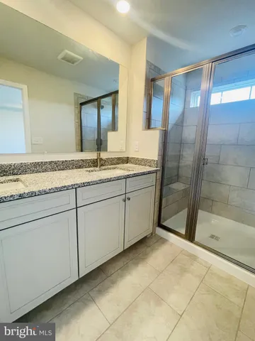 a bathroom with a granite countertop sink a mirror and a shower