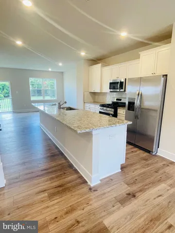 a kitchen with stainless steel appliances a refrigerator a stove a sink cabinets and wooden floor