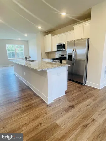 a kitchen with stainless steel appliances granite countertop a refrigerator a sink a stove a microwave and wooden floors