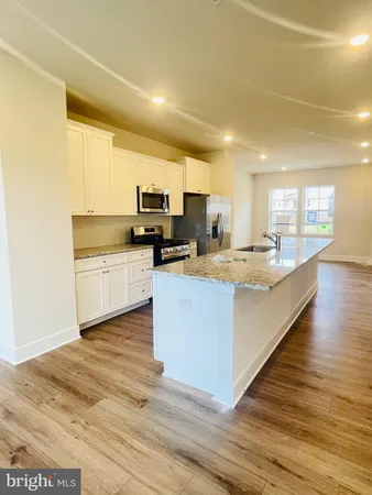 a large kitchen with kitchen island a sink a counter top space and cabinets