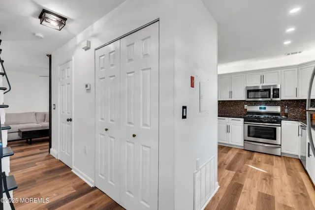 a view of a kitchen with white cabinets and stainless steel appliances