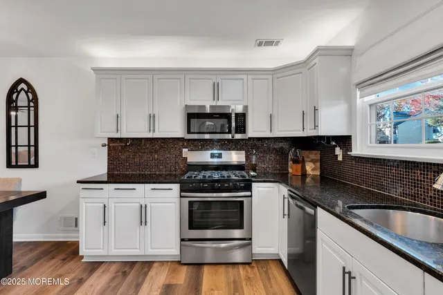 a kitchen with granite countertop a stove top oven and cabinets