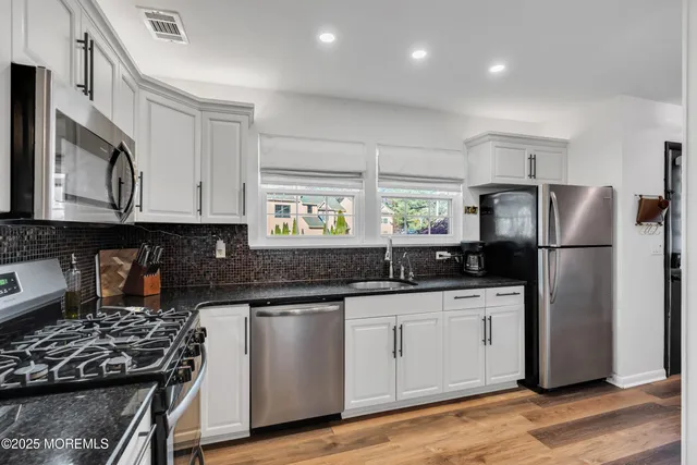 a kitchen with granite countertop a sink stove and refrigerator