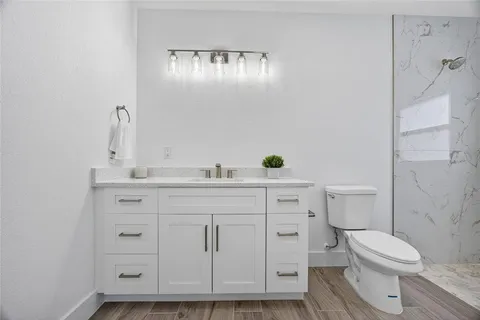 a bathroom with a granite countertop toilet sink and mirror