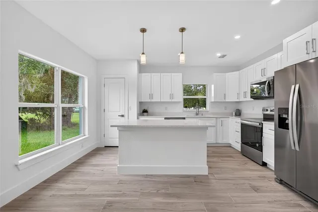 a kitchen with white cabinets and a window