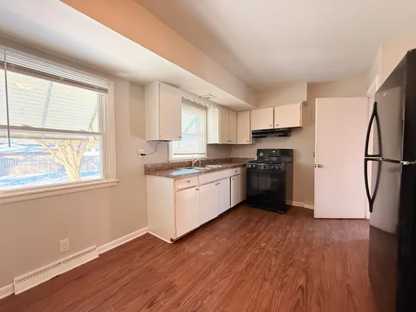 a kitchen with a refrigerator wooden floor a window cabinets and stainless steel appliances
