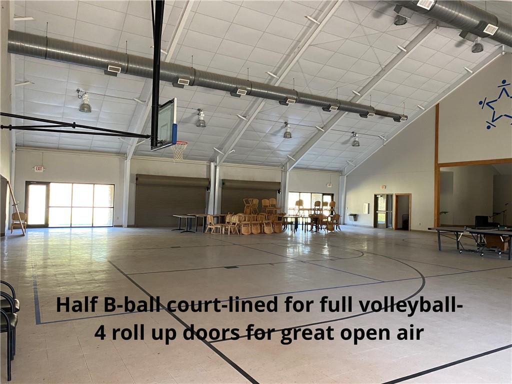8524 Youth Ranch Road Mulberry, AR 72947 - Photo 10 of 40 Spacious multi-purpose room featuring a half-basketball court with volleyball line markings, high vaulted ceilings, exposed ductwork, and multiple roll-up doors