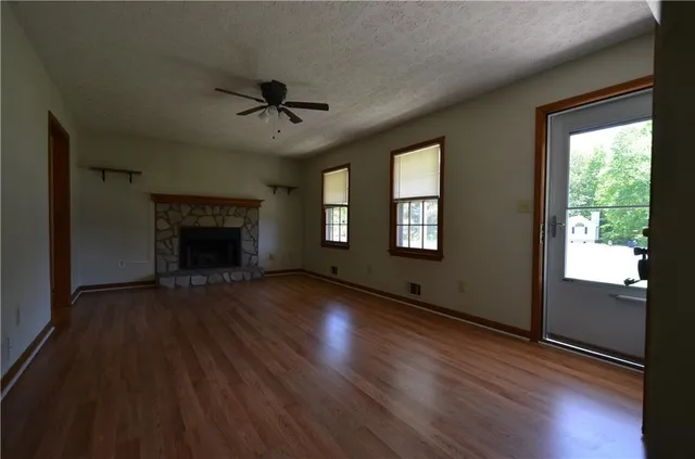an empty room with wooden floor a fireplace and windows