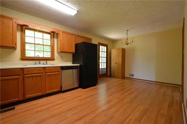 a kitchen with stainless steel appliances granite countertop a refrigerator a sink and dishwasher with wooden floor