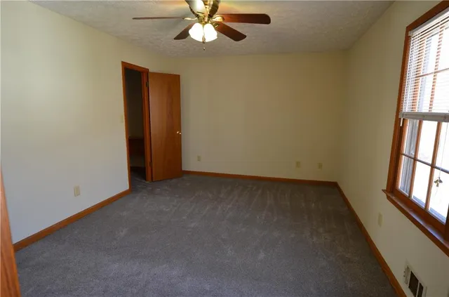 an empty room with windows and fan