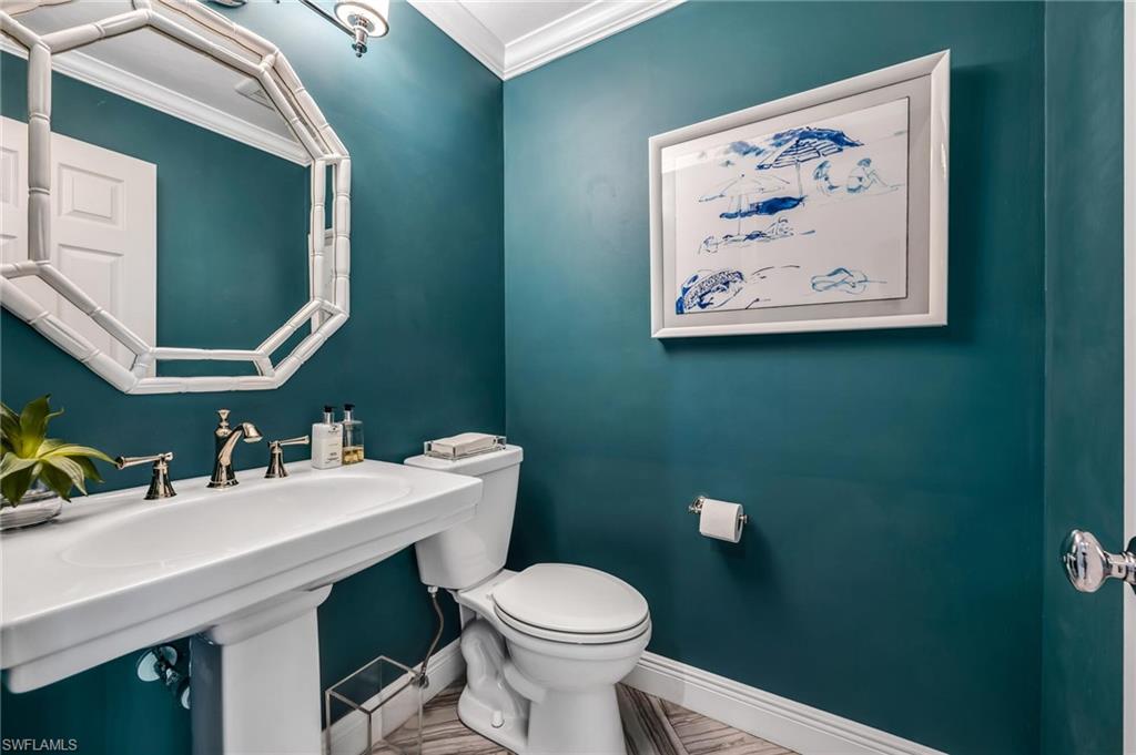 1966 Imperial Golf Course Boulevard Naples, FL 34110 - Photo 14 of 32 a bathroom with a toilet a sink and mirror