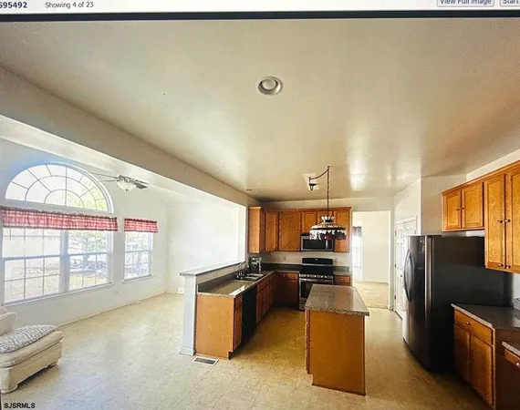 a kitchen with stainless steel appliances kitchen island granite countertop a refrigerator and a stove top oven