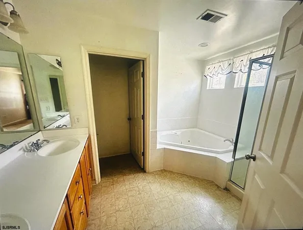 a bathroom with a tub sink vanity granite and a mirror