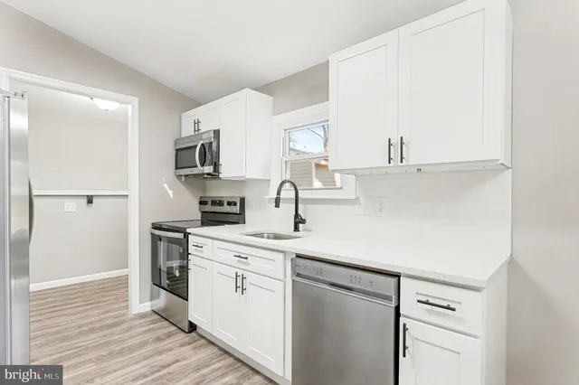 a kitchen with granite countertop a sink cabinets stainless steel appliances and a window