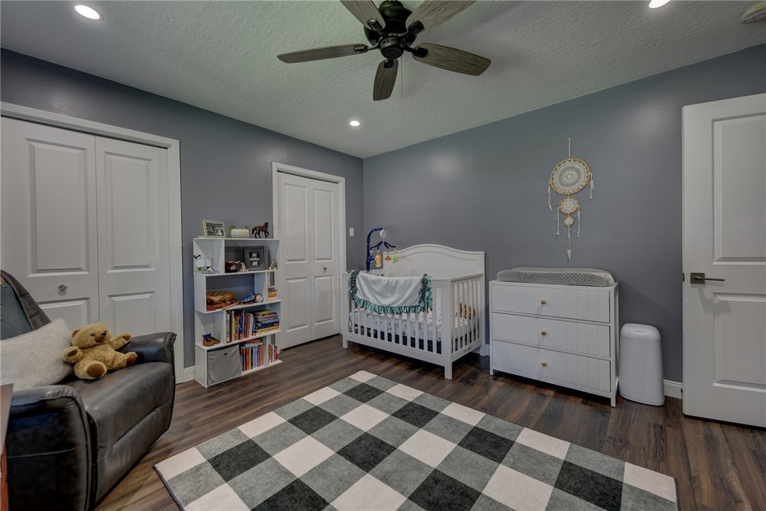 1600 Pecan Street Brenham, TX 77833 - Photo 17 of 33 Bedroom featuring wood-style flooring, two closets, a textured ceiling and baseboards