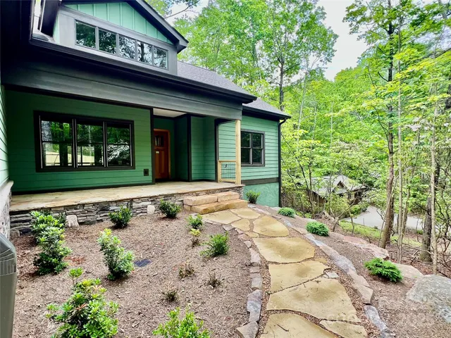 a view of a house with potted plants and a large tree