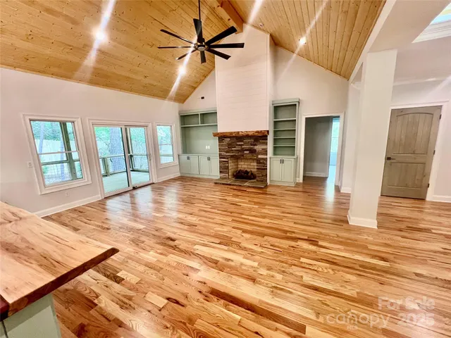 a view of an empty room with wooden floor and a fireplace