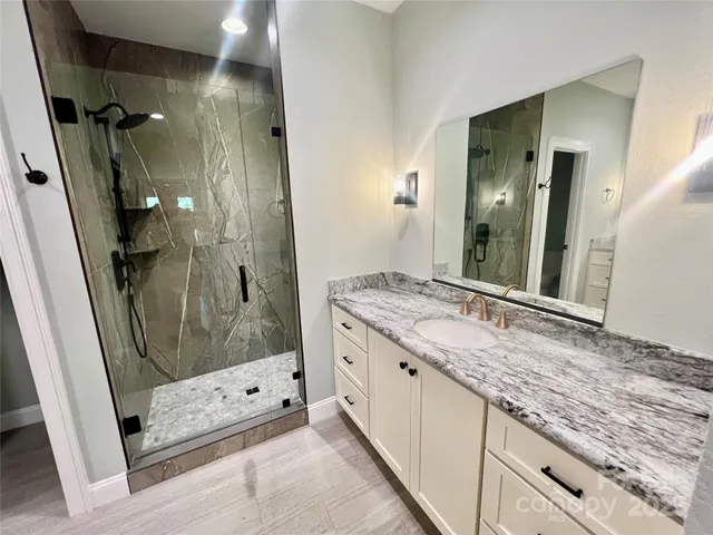 a bathroom with a granite countertop sink mirror and shower