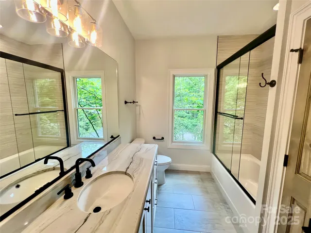 a bathroom with a granite countertop tub sink a mirror and a large window