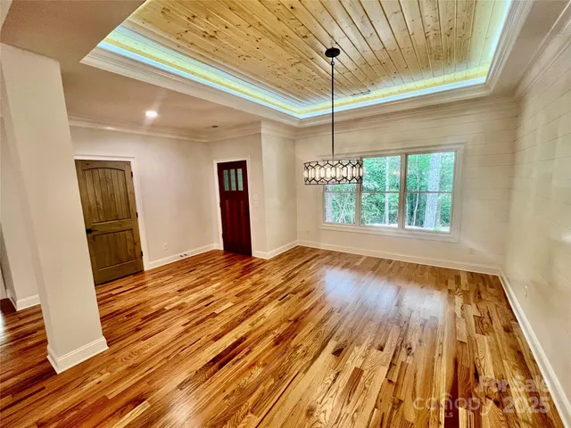 a view of an empty room with wooden floor kitchen view and a fireplace