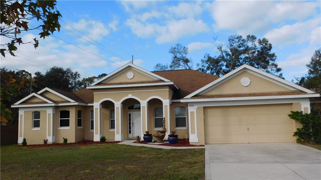 2101 Wolf Ridge Lane Mount Dora, FL 32757 - Photo 1 of 1 a view of a white house next to a yard with big trees