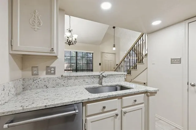 a kitchen with granite countertop a sink and white cabinets
