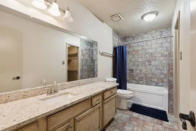 a bathroom with a granite countertop sink a toilet a mirror and bathtub