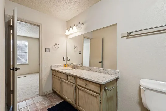 a bathroom with a granite countertop sink a toilet and a mirror