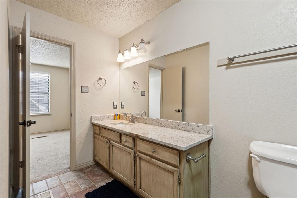 449 Harris Street, Unit 103B Coppell, TX 75019 - Photo 24 of 26 a bathroom with a granite countertop sink a toilet and a mirror