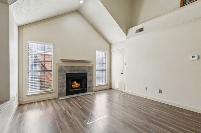 a view of an empty room with wooden floor fireplace and a window