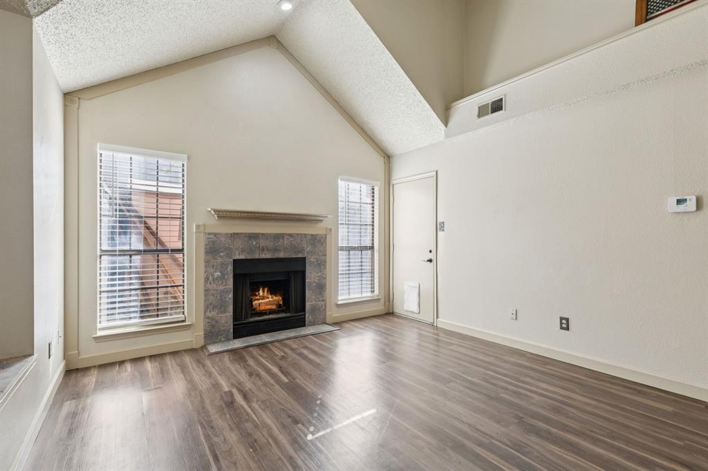 449 Harris Street, Unit 103B Coppell, TX 75019 - Photo 5 of 26 a view of an empty room with wooden floor fireplace and a window