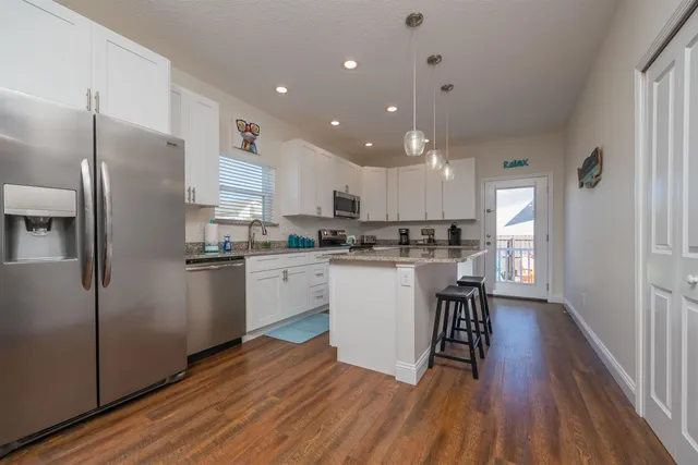 a kitchen with stainless steel appliances granite countertop a sink a refrigerator and a granite counter tops