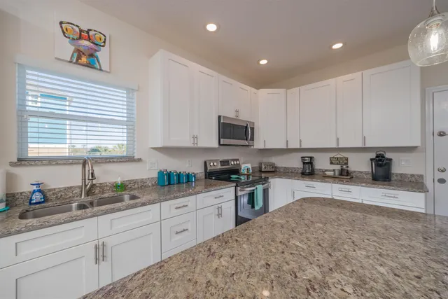 a kitchen with stainless steel appliances granite countertop a stove a sink a microwave a center island and chairs