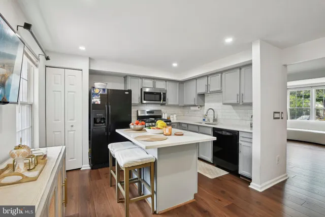 a kitchen with a refrigerator a stove top oven a sink dishwasher and white cabinets with wooden floor