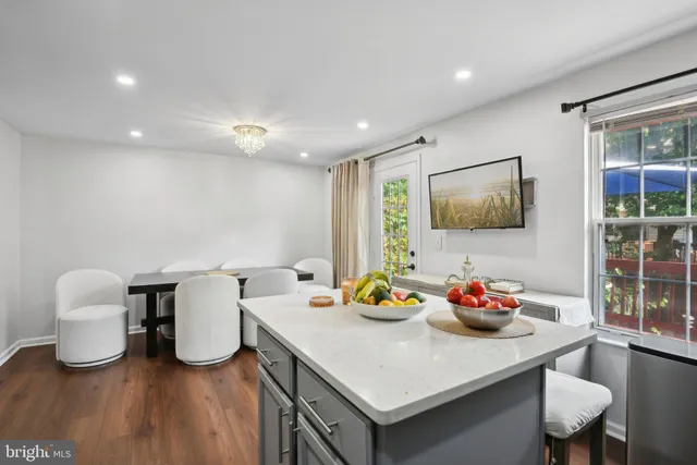 a kitchen with stainless steel appliances a kitchen island hardwood floor sink stove dining table and chairs