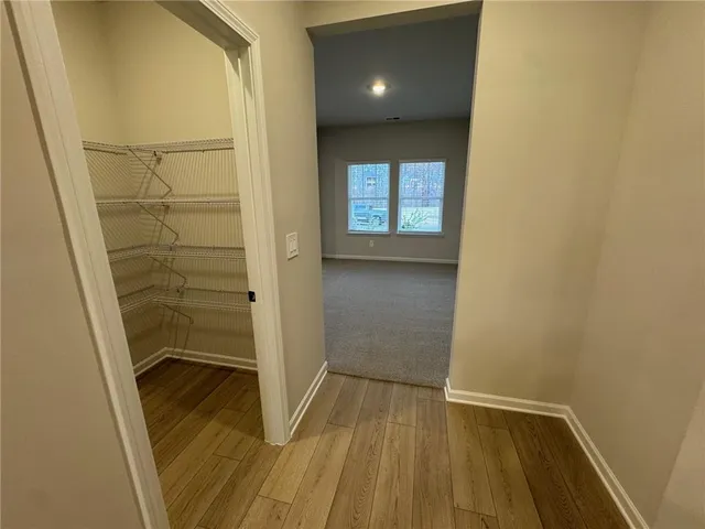 a view of an empty room with window and wooden floor