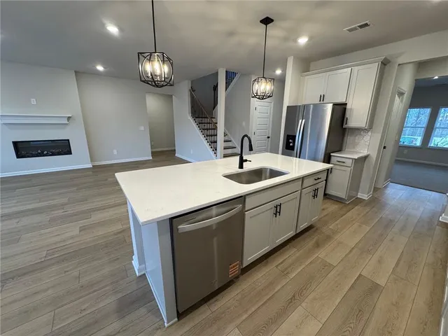 a kitchen with stainless steel appliances granite countertop a sink a oven and a wooden floor