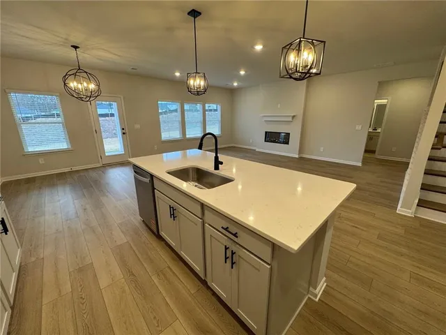 a kitchen with kitchen island stainless steel appliances a stove a sink and a wooden floor