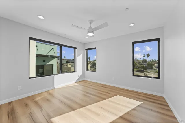 a view of an empty room with window and wooden floor