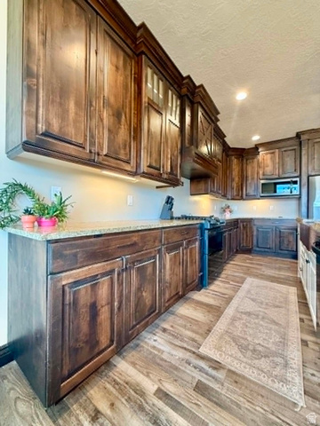 2101 Goose Ranch Road Vernal, UT 84078 - Photo 12 of 72 Kitchen featuring dark wood cabinetry, light-toned countertops, wood-finish flooring, and recessed lighting