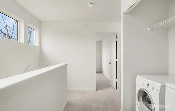 a view of kitchen and empty room with wooden floor