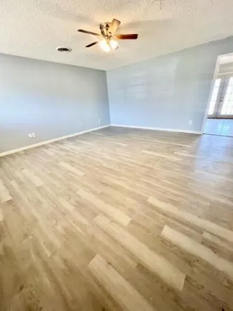 an empty room with a ceiling fan and wooden floor