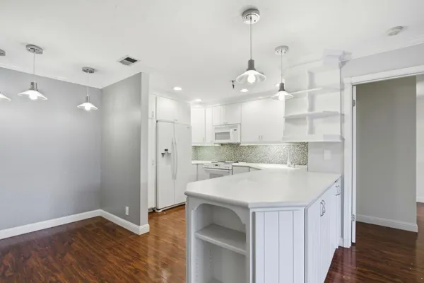 a large kitchen with a sink and dishwasher with wooden floor