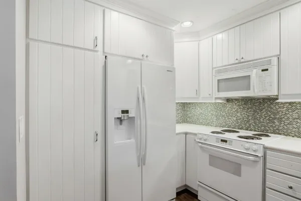 a kitchen with white cabinets and white appliances