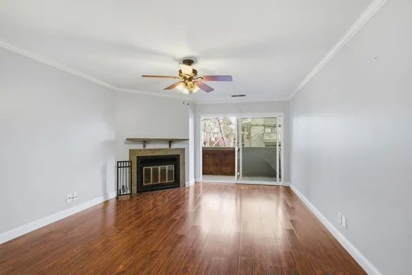 an empty room with wooden floor fireplace and windows