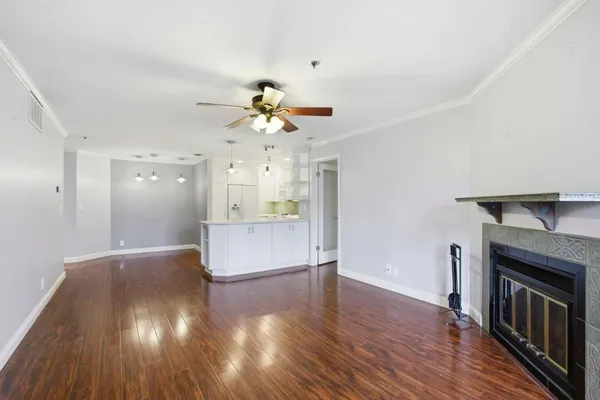 a view of an empty room with wooden floor and a fireplace