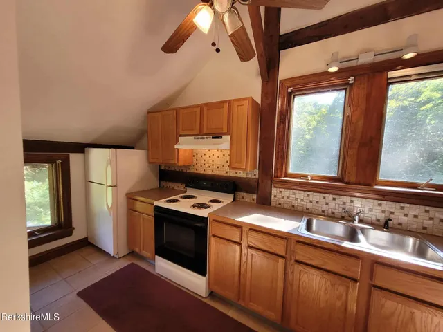 a kitchen with stainless steel appliances granite countertop a sink a stove and a refrigerator with wooden floor