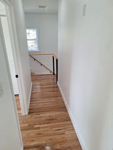a view of a hallway with wooden floor and stairs